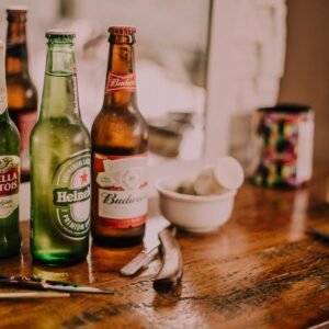 Beer bottles and barber tools on a wooden barbershop counter with a blurred mirror reflection.
